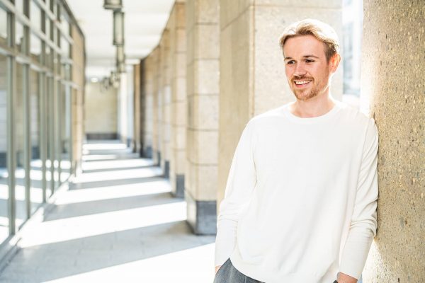 Junger Mann vor Steinwand in hellem Licht – authentisches Männerportrait in NRW