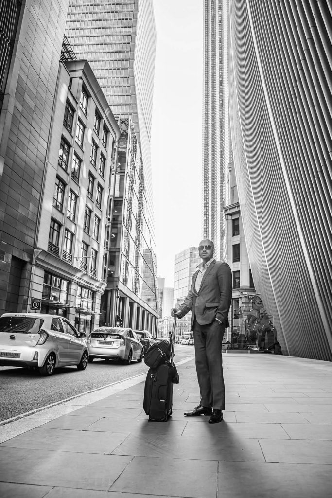 Urbanes Business Portrait eines Mannes mit Koffer in schwarz-wieß – Businessreise in Köln