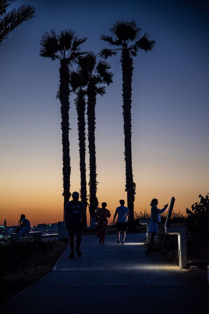 Menschen bei Abendspaziergang unter Palmen bei Sonnenuntergang – Zypern