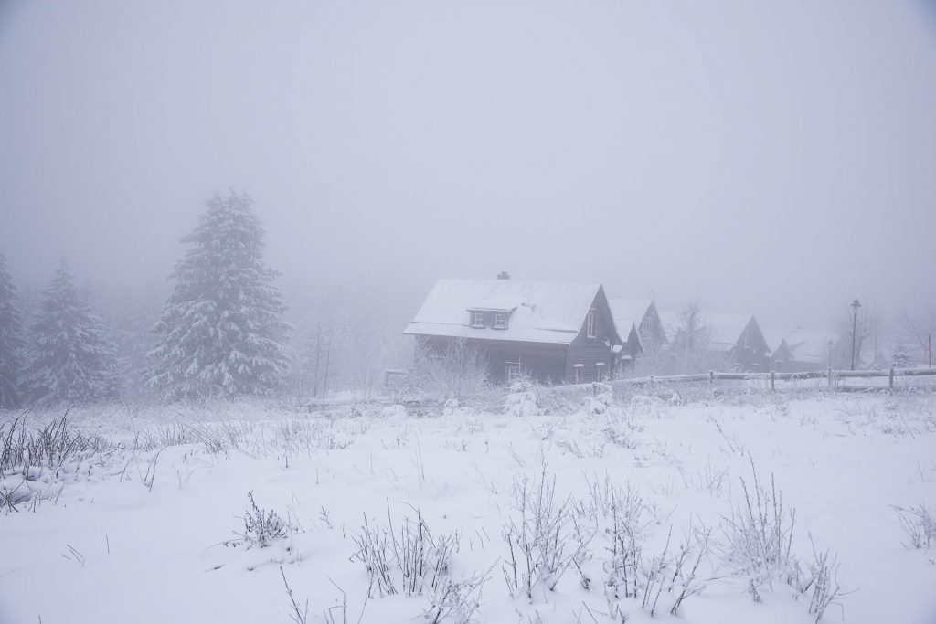Verschneite Hütten in mystischer Nebellandschaft