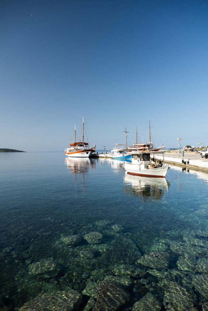 Boote im Hafen bei blauem Himmel auf klarem Wasser.