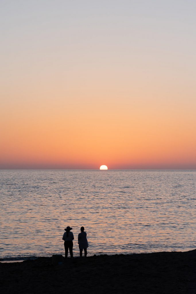 Zwei Menschen am Strand beim Sonnenuntergang am Meer