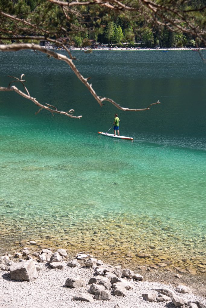 Person auf einem Stand-Up-Paddle auf türkisgrünem See