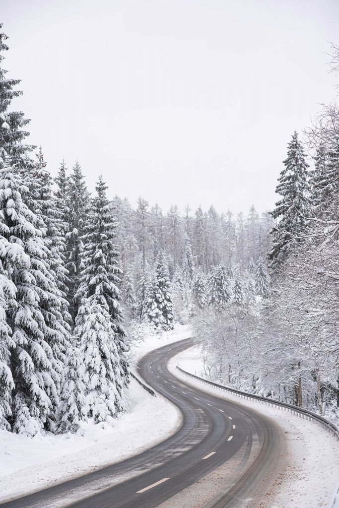 Verschneite Straße schlängelt sich durch einen Winterwald