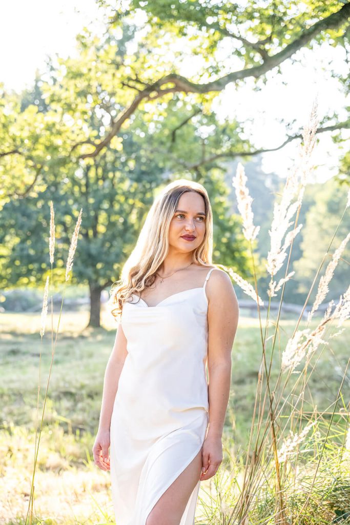 Verträumtes Wiesenshooting NRW – Frau schaut zur Seite in einer Wiese im Gegenlicht