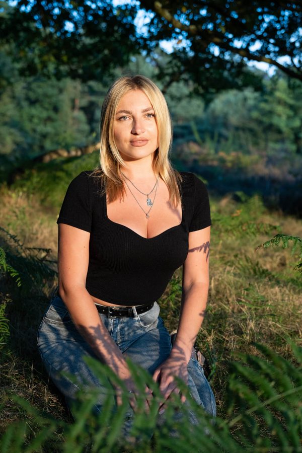 Junge Frau im natürlichen Licht einer Waldlichtung sitzend