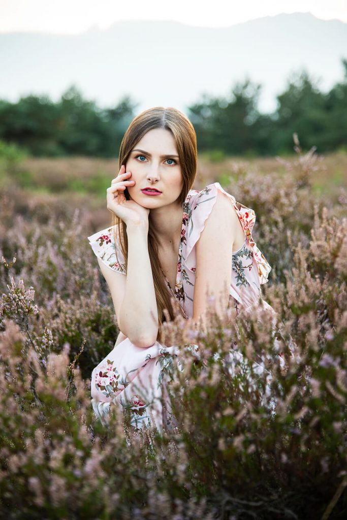 Heideshooting NRW – Frau im geblümten Kleid mit Blick zur Kamera in der Heide