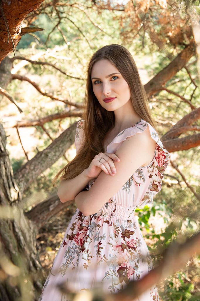 Outdoor-Portrait Köln – Romantisches Porträt einer jungen Frau in geblümtem Kleid im Wald