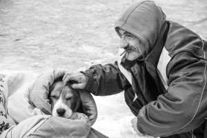 Mann mit Zigarette streichelt Hund in Decke – Schwarzweißaufnahme mit Emotion