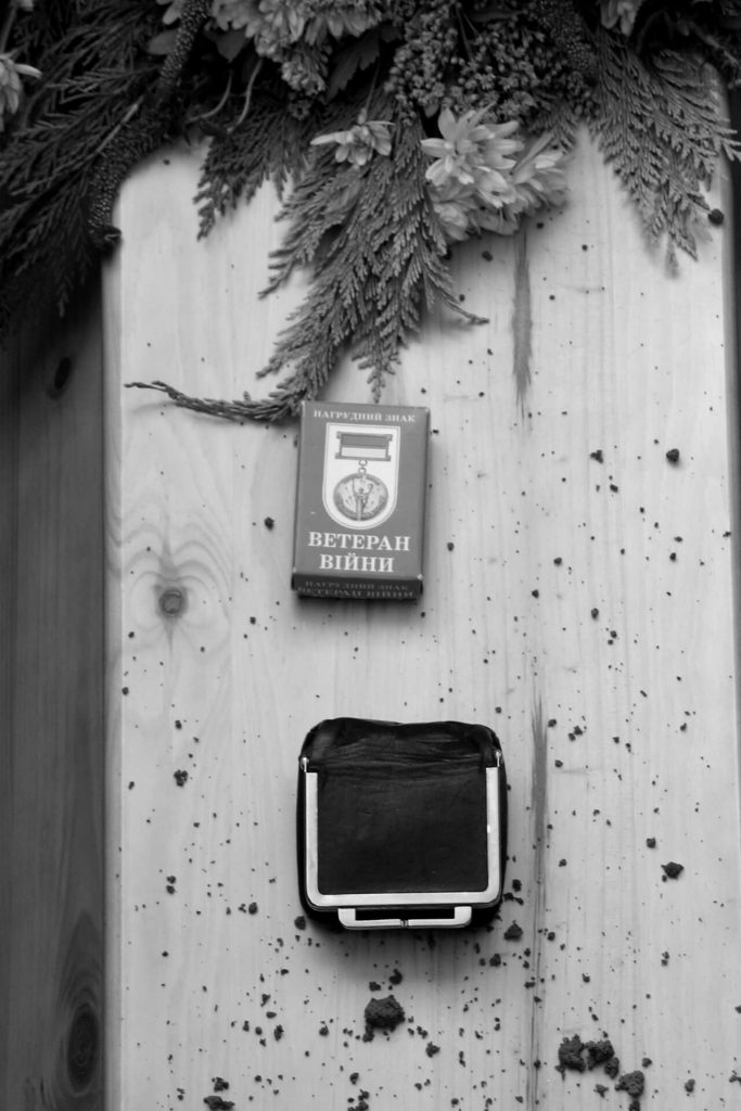 Sarg mit Blumen und Veteranenmedaille – detailreiche Schwarzweißaufnahme mit Symbolkraft