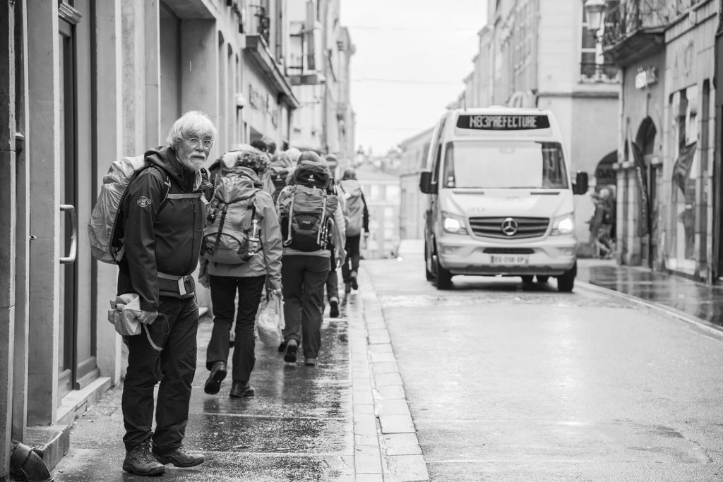 Gruppe von Wanderern in Regenkleidung in schmaler Straße – dokumentarische Streetaufnahme