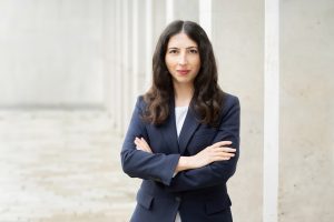 Dr. Julia Tschirka im Business-Outfit vor moderner Architektur – Expertin für Scientific Affairs, Kommunikation und pharmazeutische Projekte