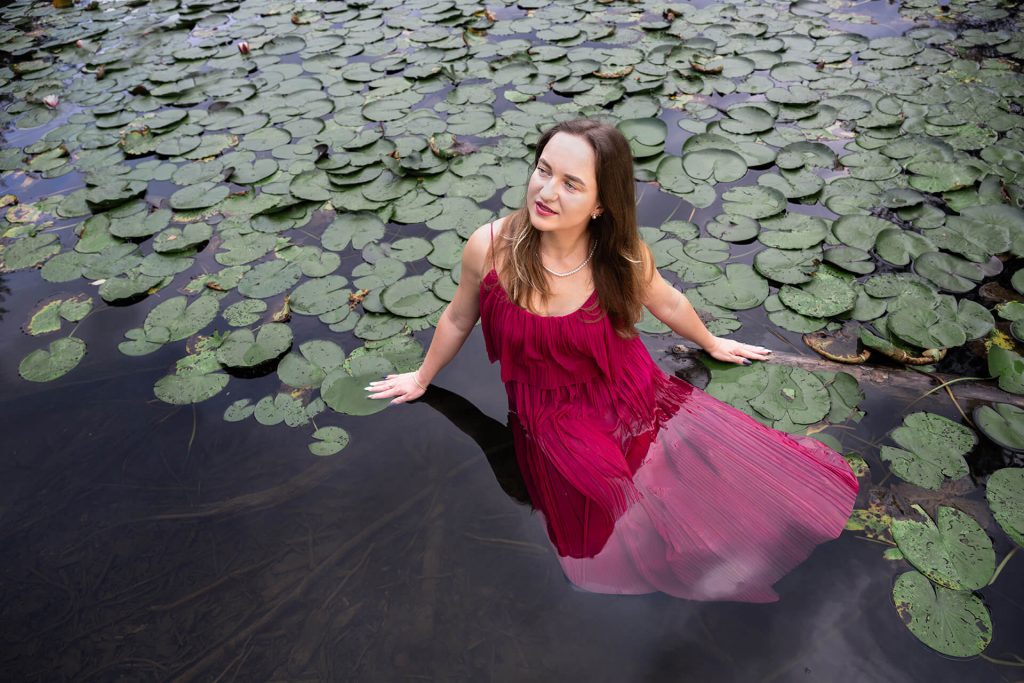 Künstlerisches Portrait einer Frau in rotem Kleid zwischen Seerosen, fotografiert von yourphotoandstory in Köln