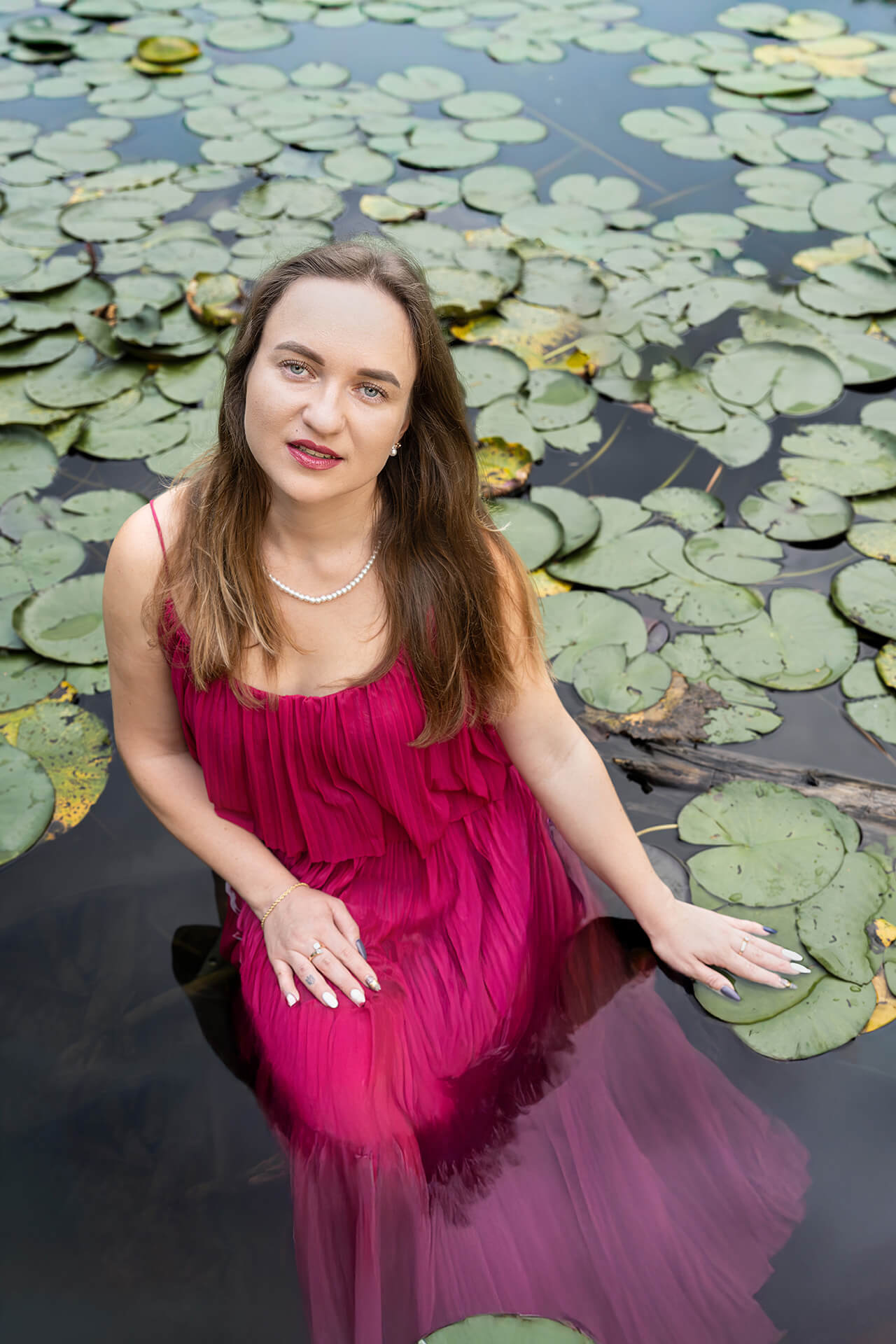 Studioporträt Köln – Frau mit schwarzem Kleid und Rose vor dunklem Hintergrund schaut direkt in die Kamera