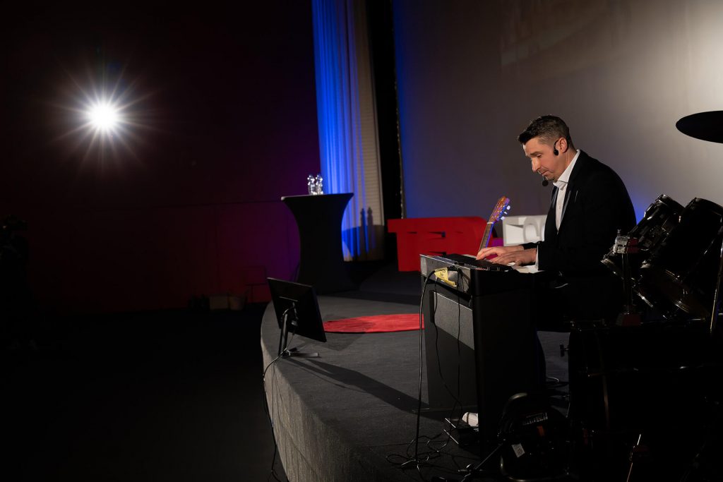 Pianist am Keyboard auf Bühne bei TEDxEssen, Prof. Dr. Samuel Stäbler mit der Rede Inspiring Human Generosity: Academic Insights from Street Music