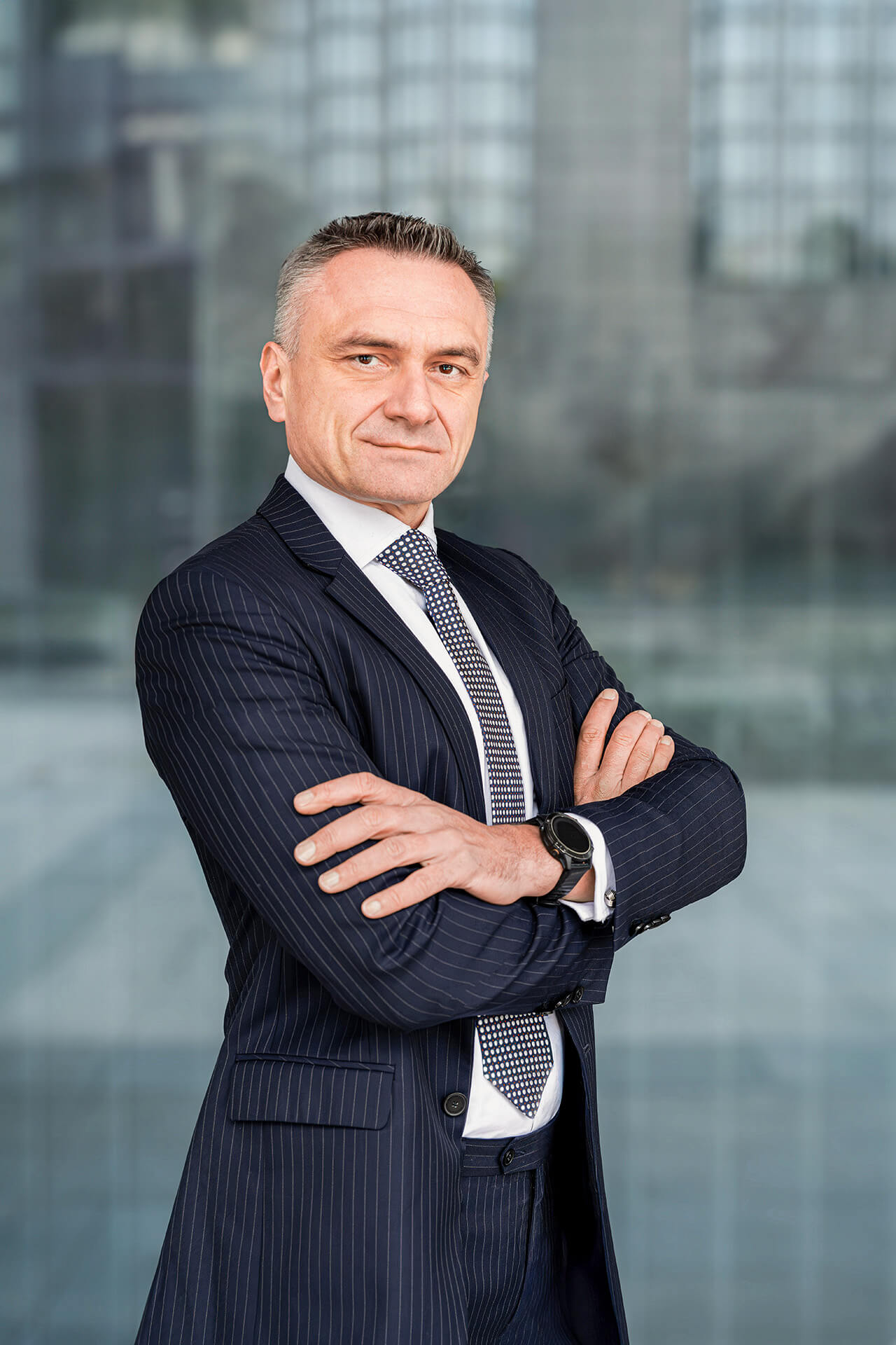 Business-Porträt eines Mannes im Anzug mit Rollkoffer in moderner Großstadt-Kulisse in London