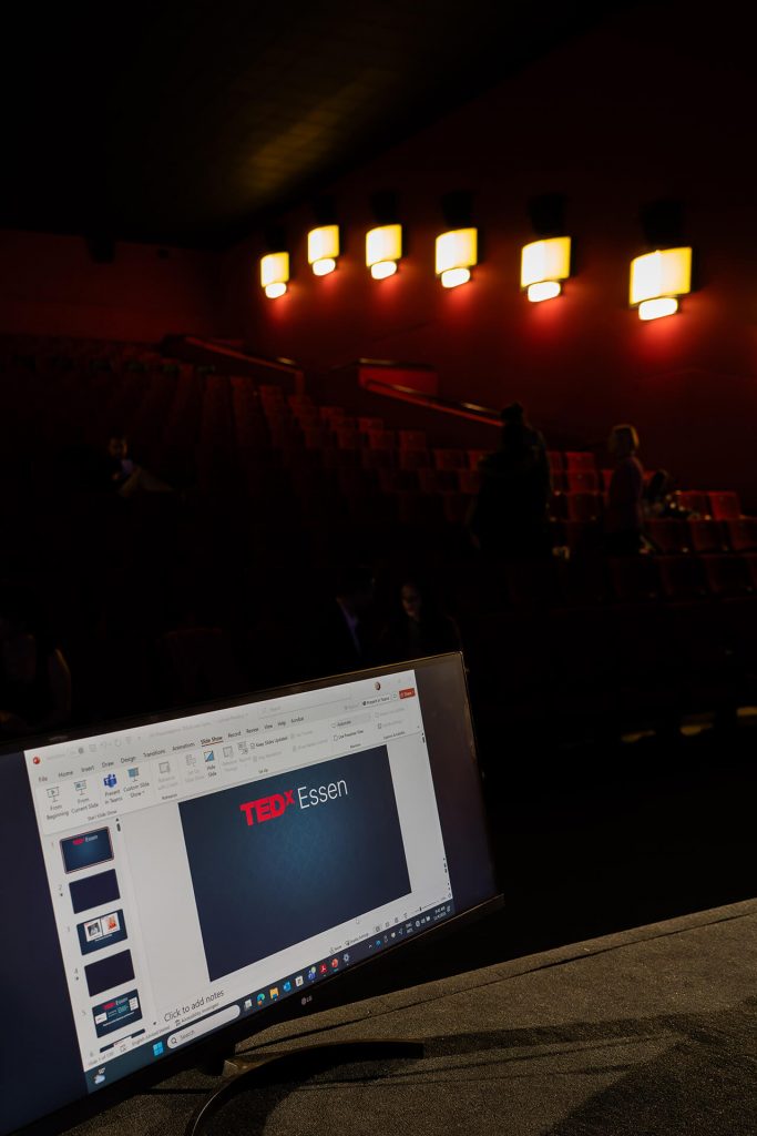 Präsentationsbildschirm mit TEDxEssen-Folie im leeren Kinosaal