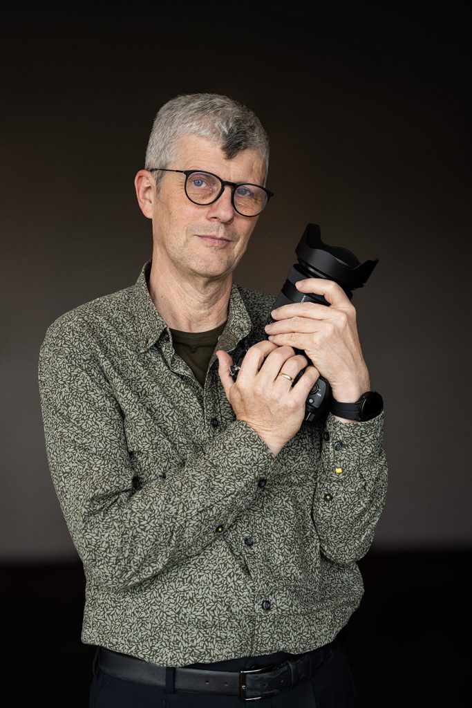 Authentisches Business-Portrait eines Fotografen mit Kamera in der Hand, aufgenommen von yourphotoandstory.