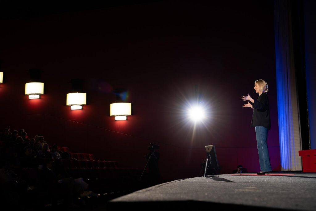 Rednerin Dr. Monika Hein auf der Bühne mit Publikum im Schatten bei TEDxEssen, Rede: The Voice of Compassion: Reclaiming Our Power to Connect