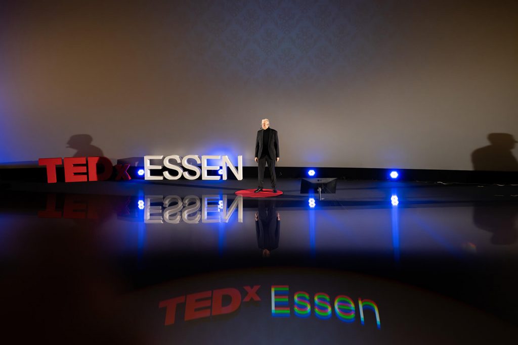TEDxEssen Bühne mit Redner, Logospiegelung und Projektion auf Boden