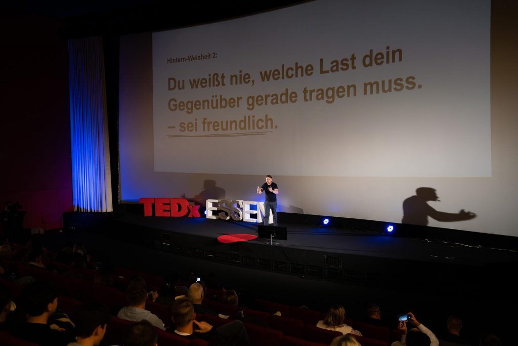 Großes Zitat auf Leinwand mit Redner auf der Bühne bei TEDxEssen