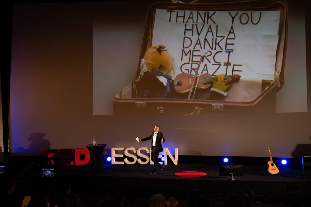 Moderator vor dem großen „Danke“-Slide auf der Bühne bei TEDxEssen