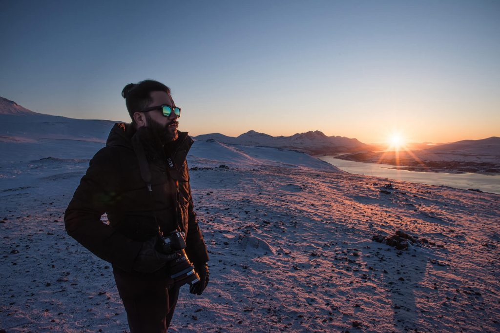 Person steht in einer winterlichen Berglandschaft im goldenen Sonnenuntergang.
