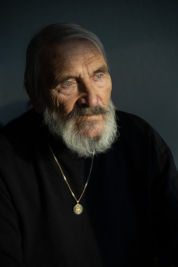 Nachdenkliches Porträt eines älteren Mannes mit Bart, Hand am Kinn, Schmuck an Fingern und Handgelenk