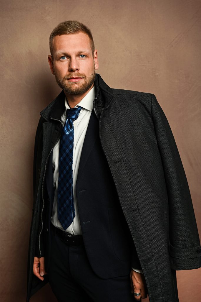 Stilvolles Business-Porträt Mann in Köln in einem Mantel, lessig geworfen über die Schulter.