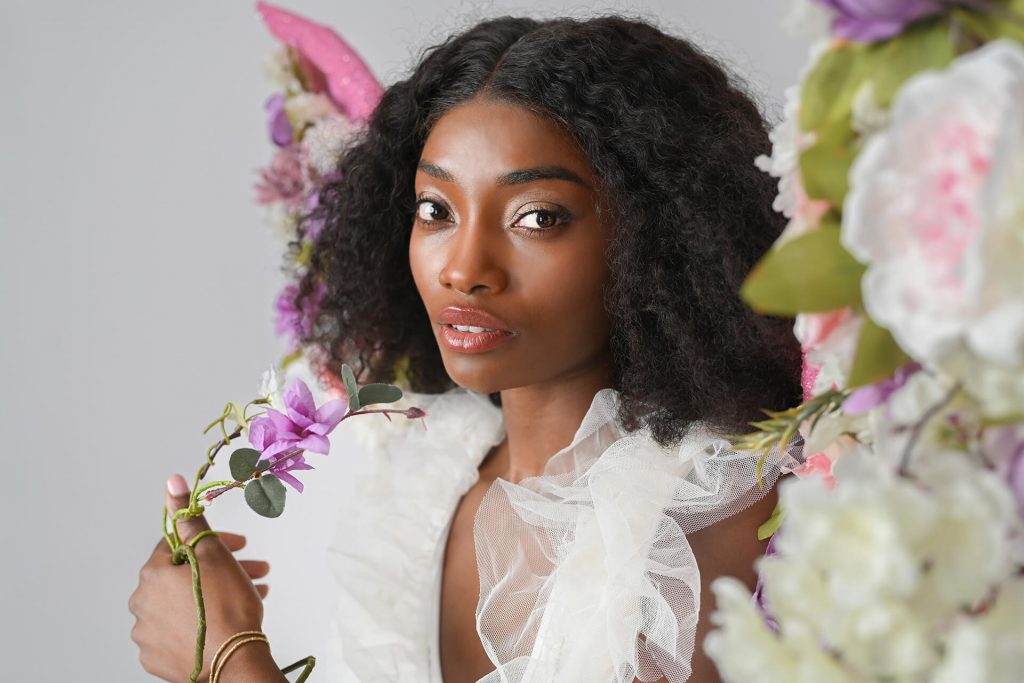 Fine-Art-Porträt einer schwarzen Frau mit floraler Rahmung und einer Blume in der Hand