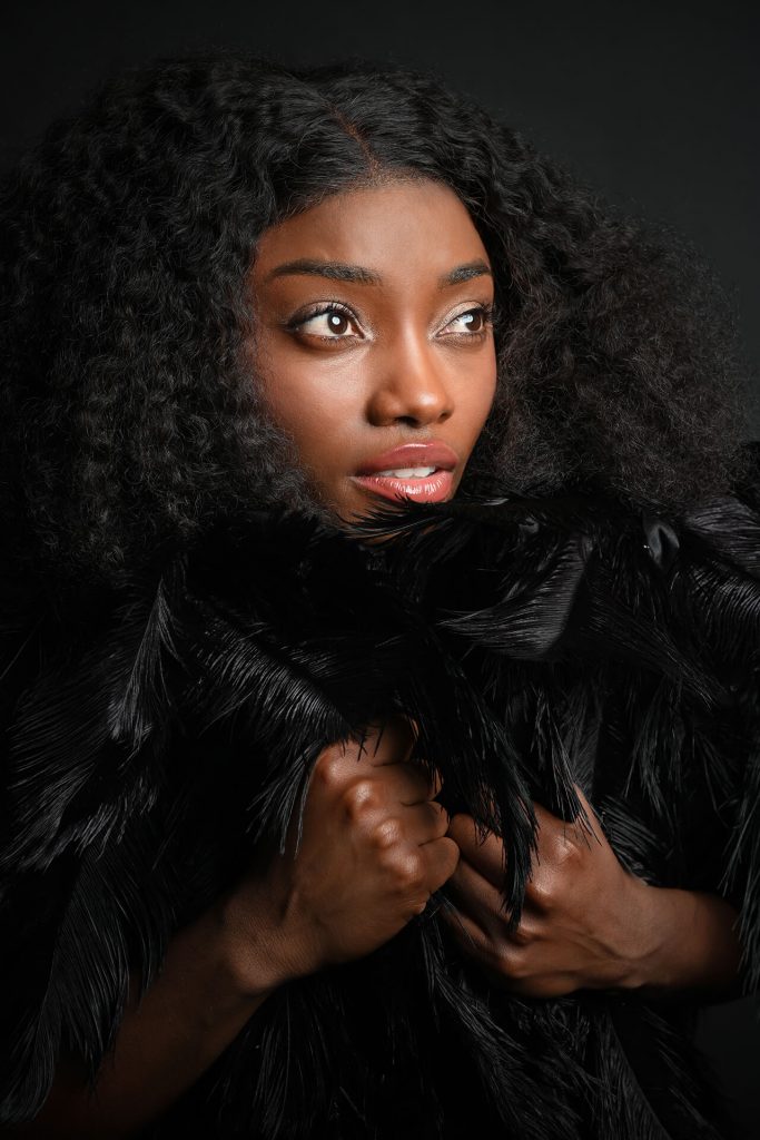 Fine-Art-Porträt einer Frau mit Blick nach oben und schwarzem Federdetail