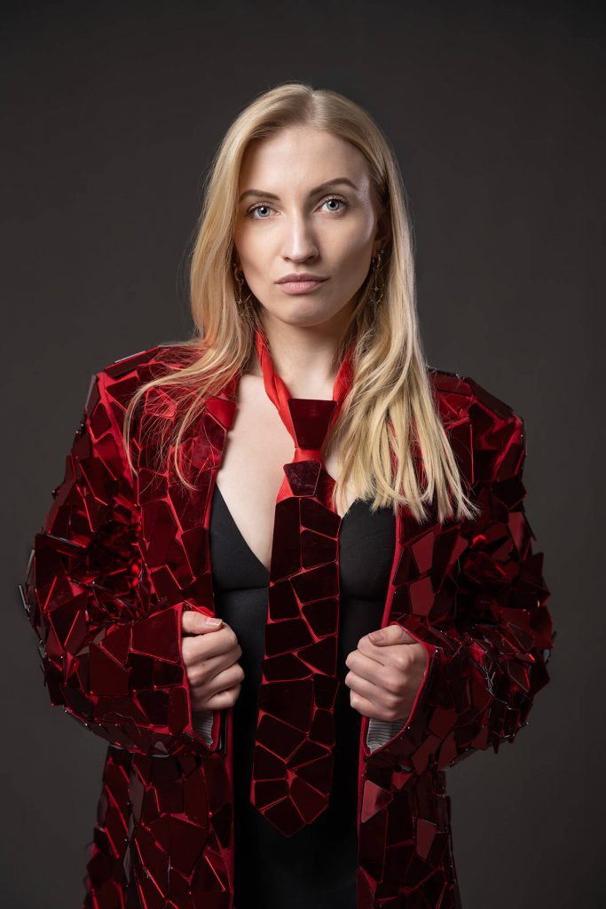 Frau mit roter Jacke und Krawatte bei einem Portraitshooting im Studio