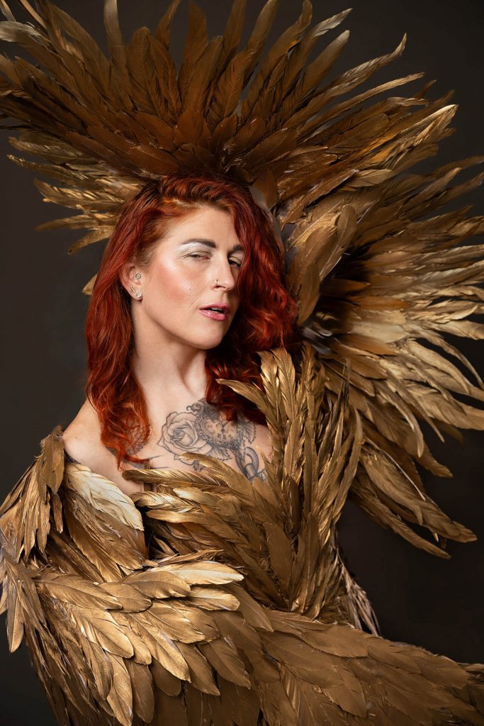Frau n goldenem Federkostüm bei einem Fine Art Shooting