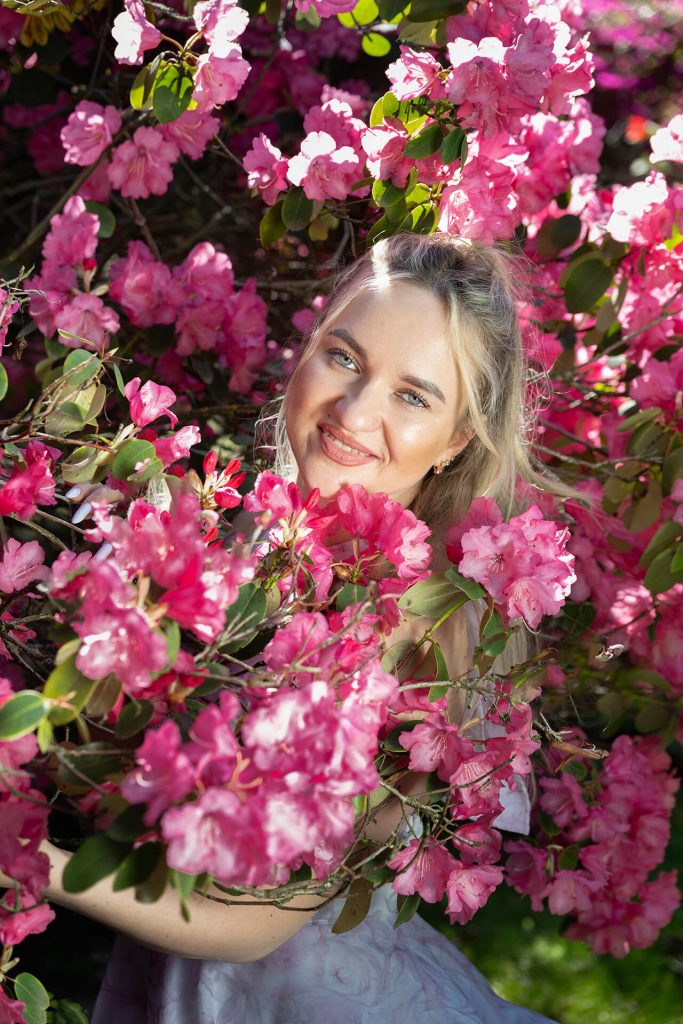 Romantisches Portrait einer Frau zwischen rosa Pfingstrosen und grünen Blättern