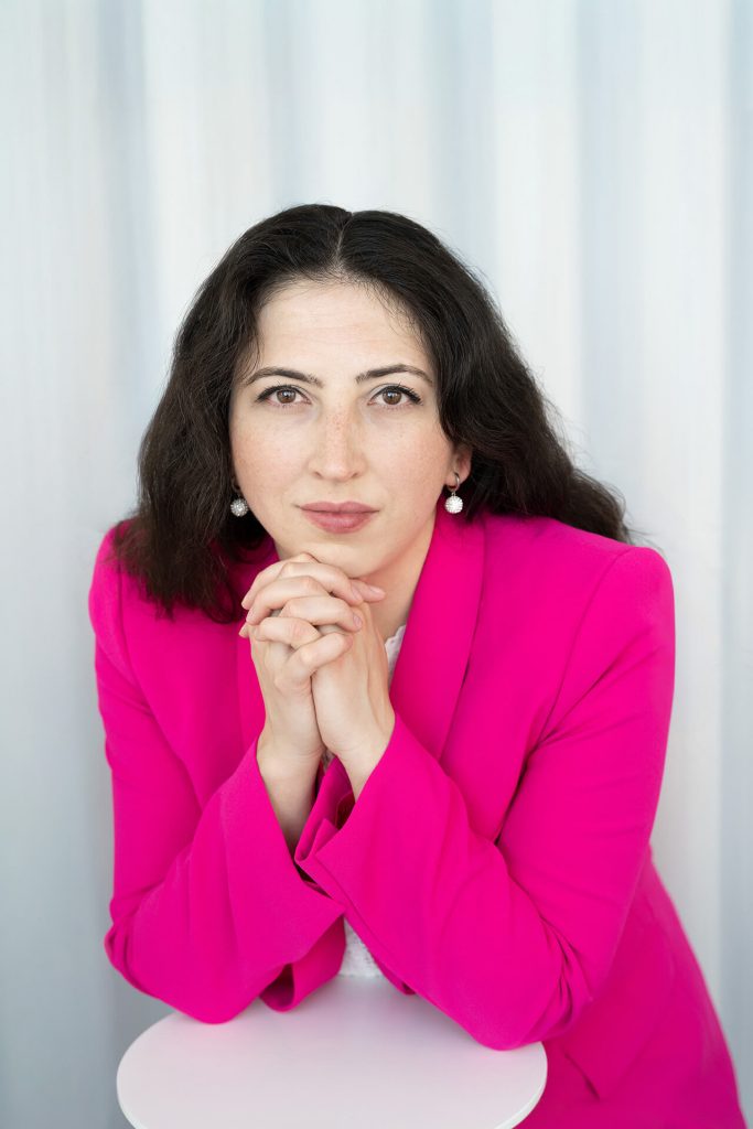 Julia Tschirka blickt aufmerksam in die Kamera und stützt die Hände unter dem Kinn